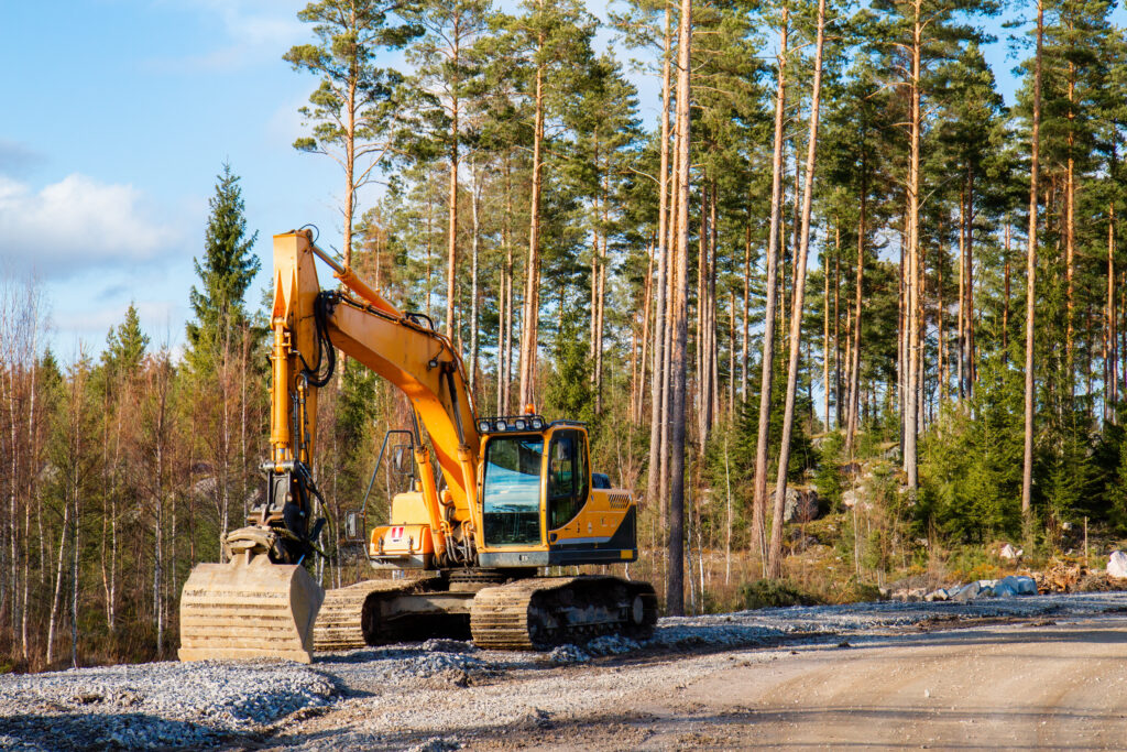 Yellow excavator building a road deep in the forest.